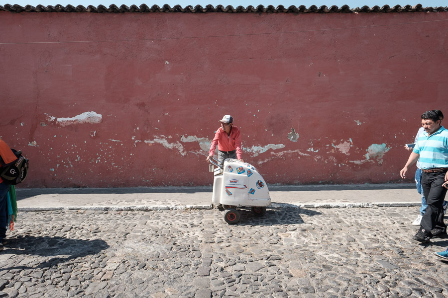 An ice cream vendor waits for customers to come his way on the hot cobblestone streets.