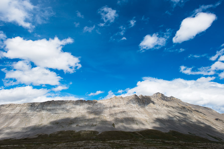 Clouds cast shadows on the mountain peaks reaching for them.