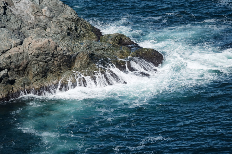 Heavy surf surges over rocky shore.