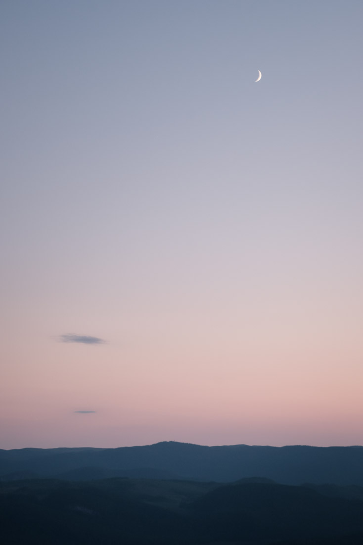 Moon rising over undulating valleys.
