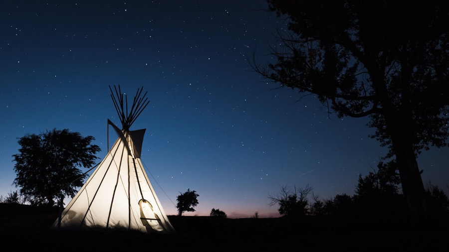 A teepee lit up against the tapestry of the night sky.Context: A scene from the dark sky preserve that is Grasslands National park. &ndash;link forthcoming&ndash;